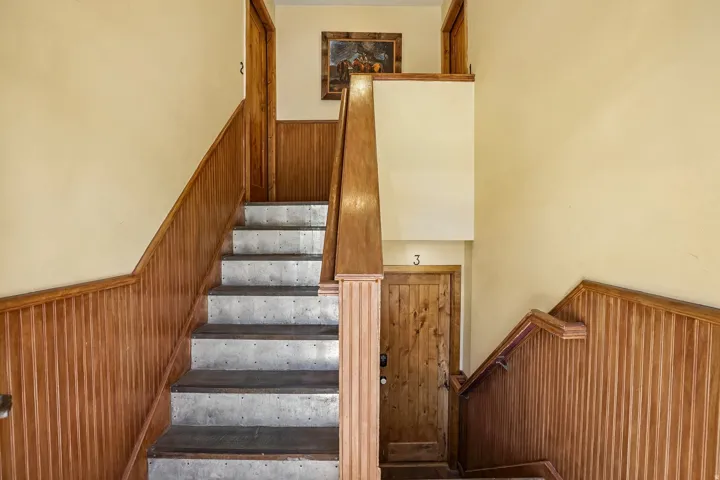 Staircase with wood-finish paneling, wood-finish risers, and light-colored treads