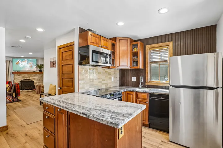 Kitchen featuring wood-finish flooring, recessed lighting, wood cabinetry, and a stone-finish countertop