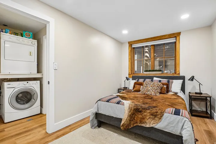 Recessed lighting, wood-finish flooring, a built-in laundry closet with stacked appliances, and a window with wood trim
