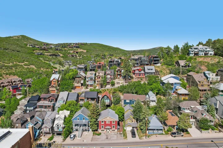 Residential properties situated on a verdant hillside with varied architectural styles and mature trees