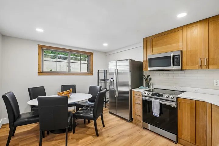 Wood-finish flooring throughout, recessed lighting, and a kitchen featuring wood cabinetry, stainless steel appliances, and light-toned countertops