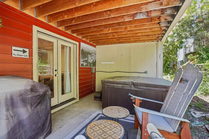 Covered patio with a spa, concrete flooring, and exposed wood beam ceiling