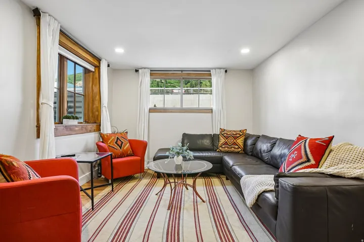 Recessed lighting illuminates this bright room featuring multiple windows with wood trim