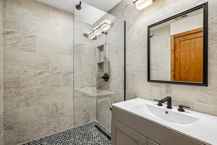 Glass-enclosed shower with pebble-tile floor and recessed shelving