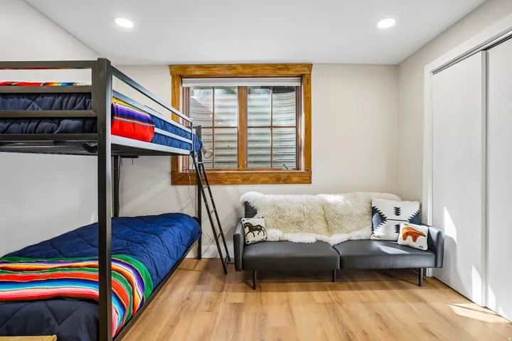Recessed ceiling lighting, wood-finish flooring, a window with wood trim, and bi-fold closet doors