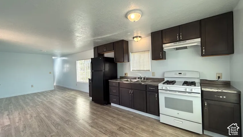 Kitchen featuring dark wood-finish cabinetry, white appliances, and a double basin sink