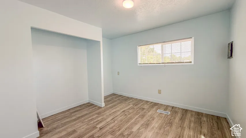 Wood-finish flooring, recessed closet space, and a window with horizontal blinds