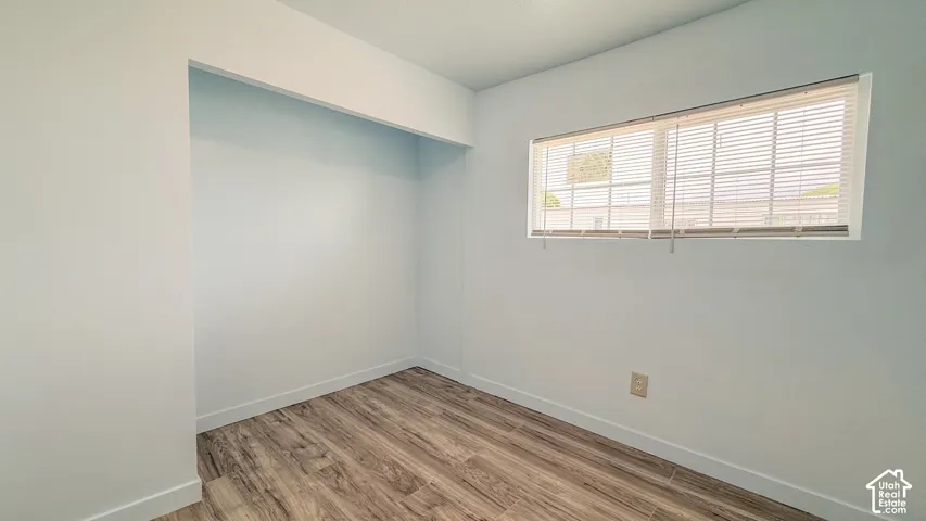 Recessed wall alcove, wood-finish flooring, white walls, and horizontal window blinds