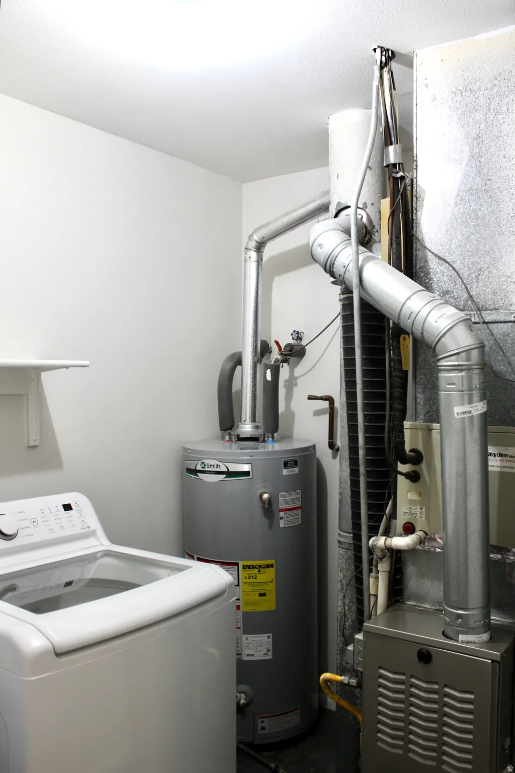 Dedicated utility space featuring a water heater, furnace, and laundry appliance