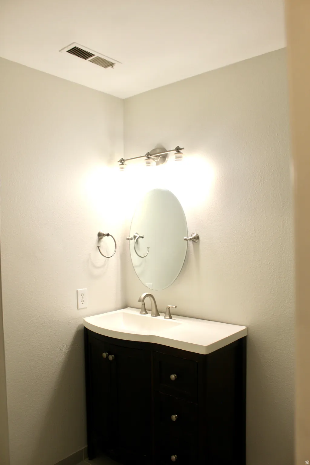 Vanity featuring an integrated basin, brushed nickel faucet, and dark wood-finish cabinetry