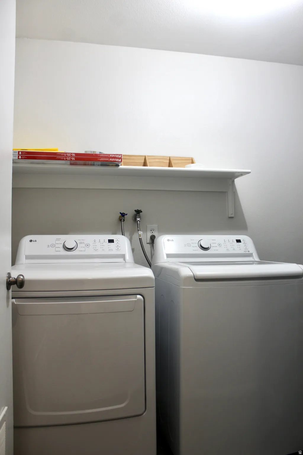 Laundry area featuring a top-load washing machine, front-load dryer, and a wall-mounted shelving unit