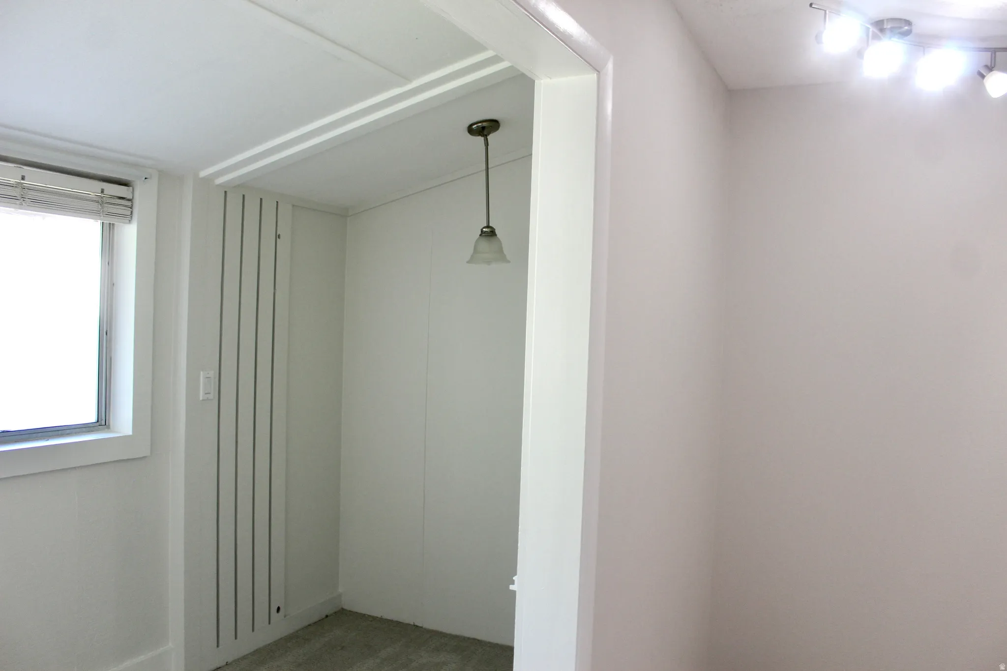 Wall-mounted track lighting, recessed ceiling, framed doorway, and a pendant light fixture