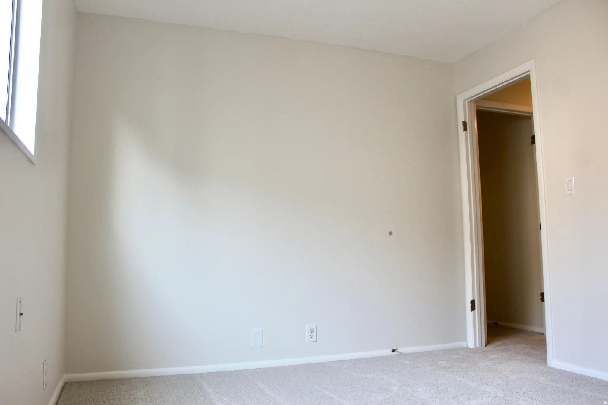 Light-toned walls, neutral carpeting, and a window providing natural illumination