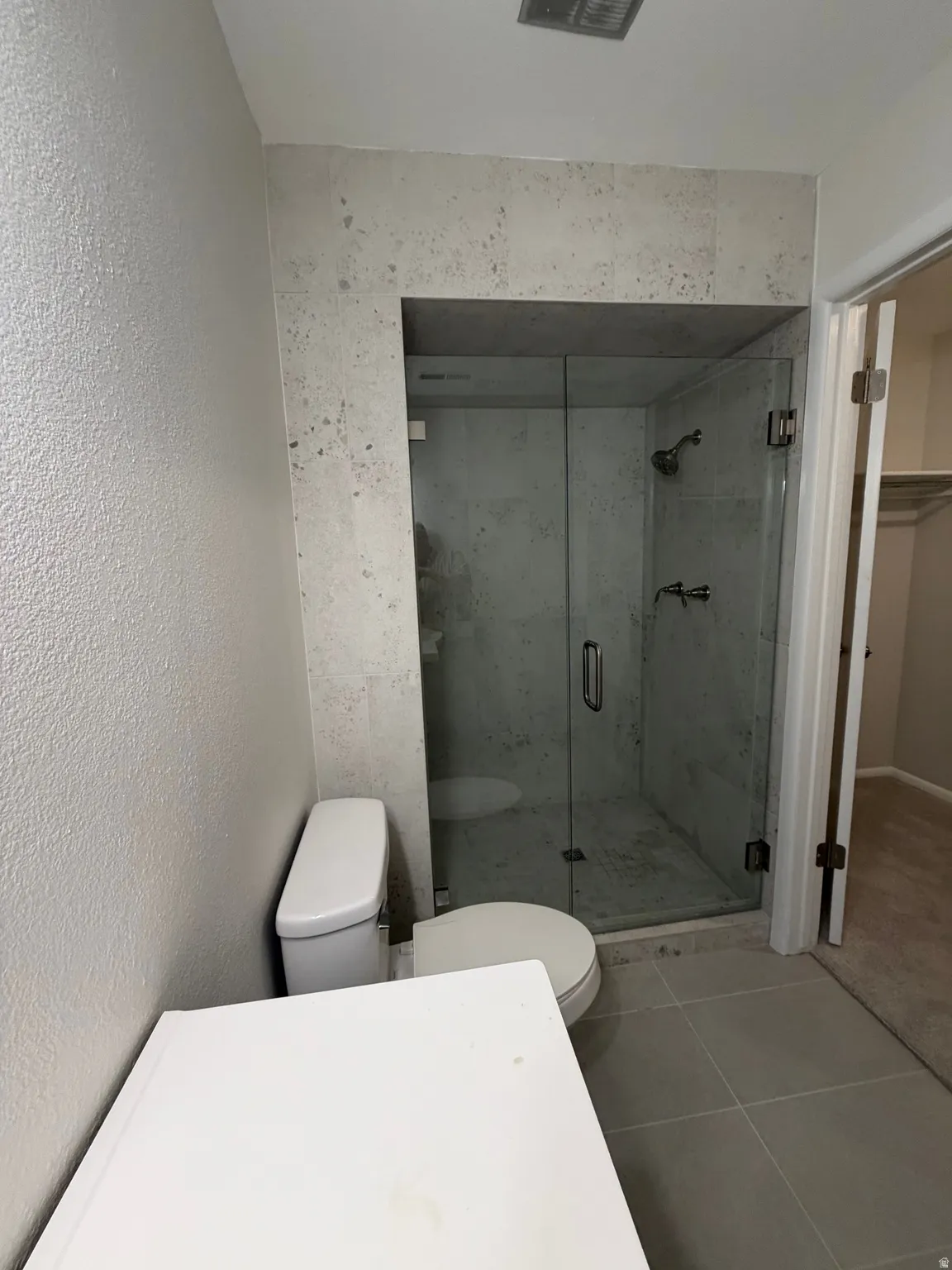 Walk-in shower with clear glass enclosure and tiled surround