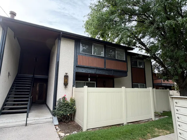 Exterior featuring stucco siding, brown accent panels, multiple windows, and a private staircase entry