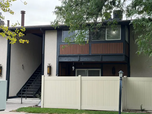 Multi-story building with textured exterior finish, wood paneling, and a white fence