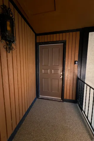 Brown paneled entry wall with black trim, dark brown door, and black metal railing