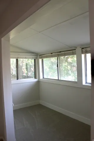 Sunroom featuring multiple windows, sloped ceiling, and carpeted flooring