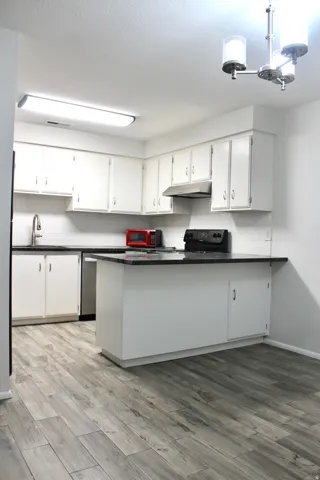 Kitchen featuring white cabinetry, dark countertops, white subway tile backsplash, and wood-finish flooring