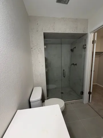 Walk-in shower with clear glass enclosure and tiled surround