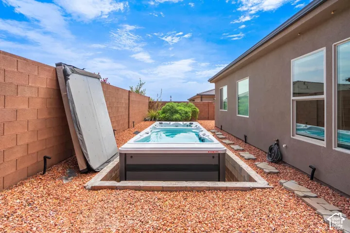 In-ground spa with a protective cover, surrounded by decorative gravel, a block wall, and stepping stones