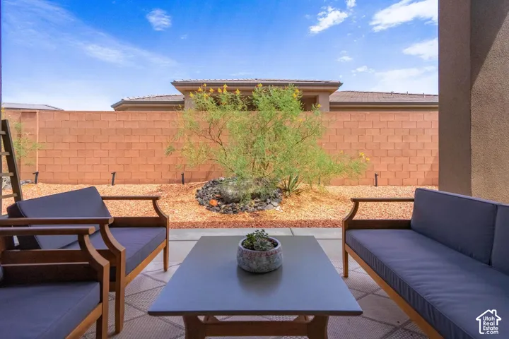Covered patio with a concrete slab, a low-maintenance xeriscape, and a block perimeter wall