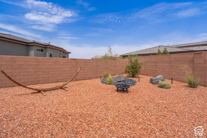 Expansive yard featuring red gravel, a decorative fire pit, and low-maintenance landscaping