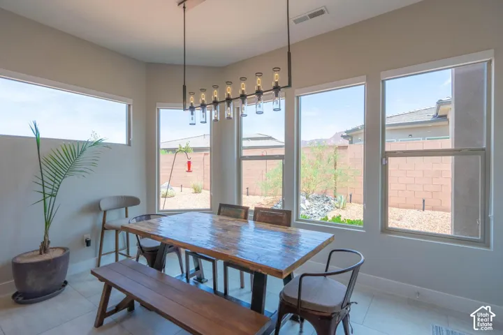 Recessed lighting with a contemporary linear chandelier, multiple large windows, and light-toned tile flooring