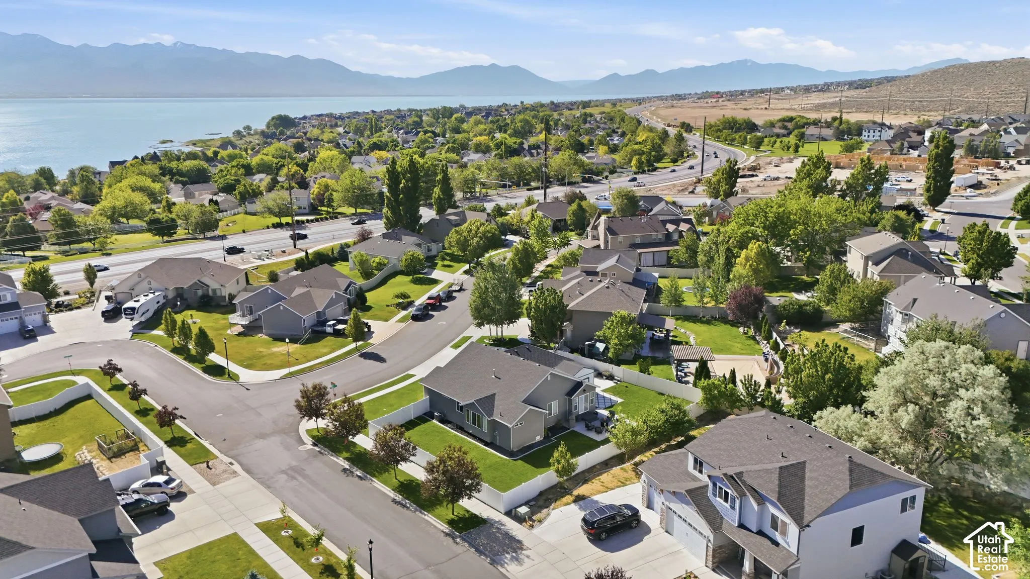 Aerial perspective of a residential neighborhood with a prominent body of water and distant mountains