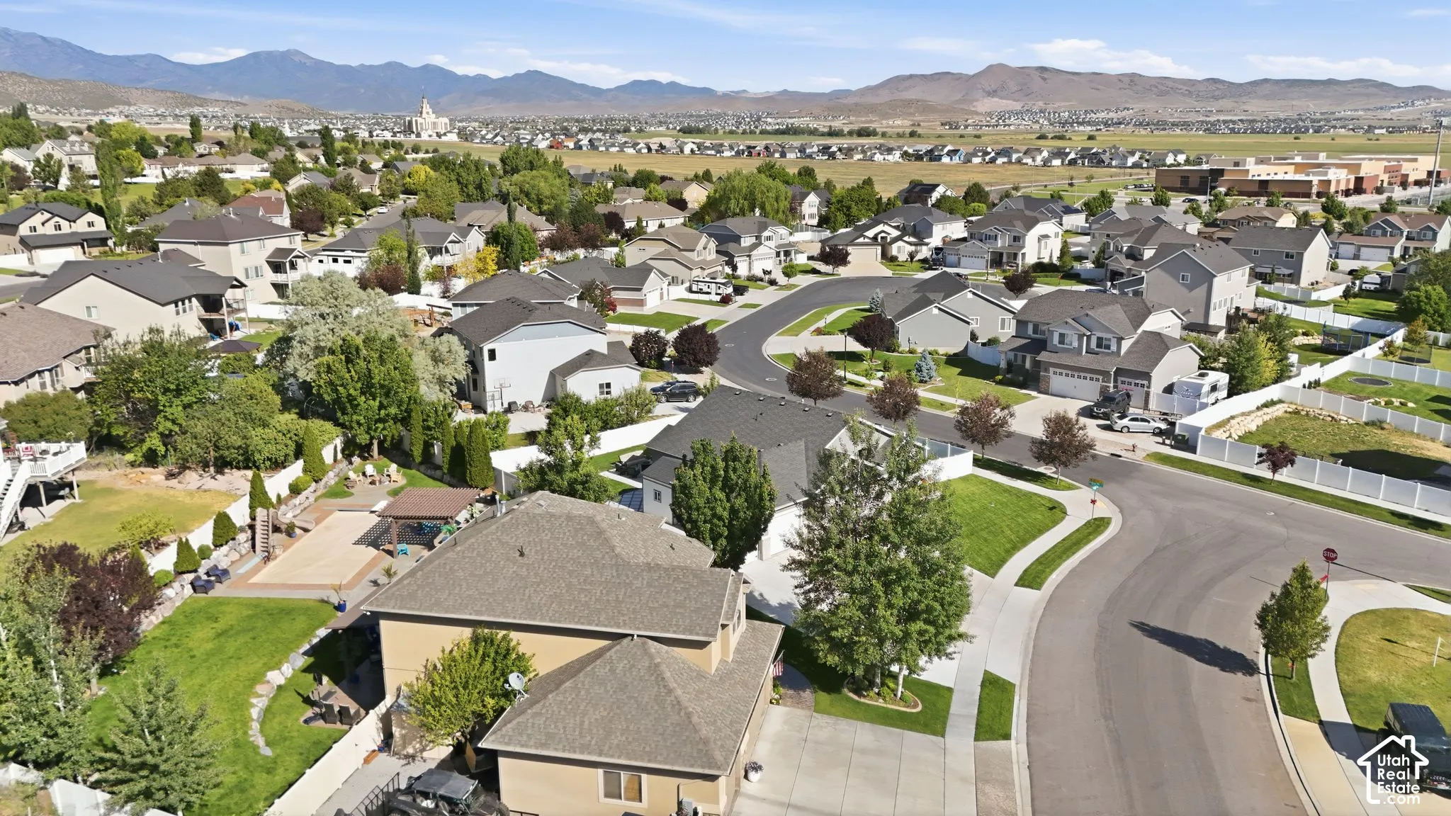 Curved street design, extensive residential housing, distant mountainous terrain, and open green spaces