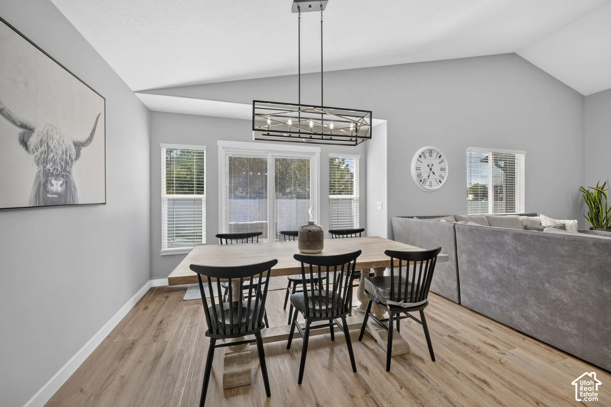 Vaulted ceilings, wood-finish flooring, and multiple windows with blinds