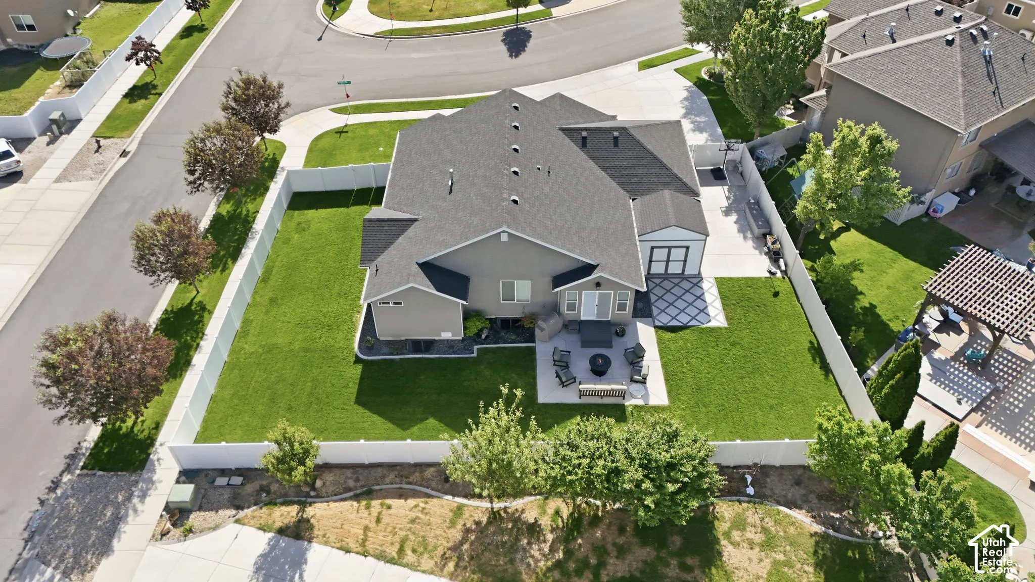 Expansive lot featuring a green lawn, privacy fencing, a paved patio, and a dedicated driveway