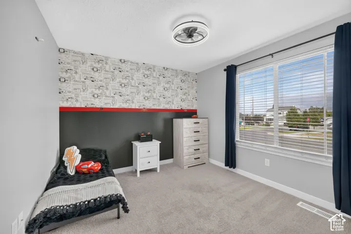 Light gray carpeting, a multi-pane window with horizontal blinds, and a contemporary ceiling fan with integrated lighting