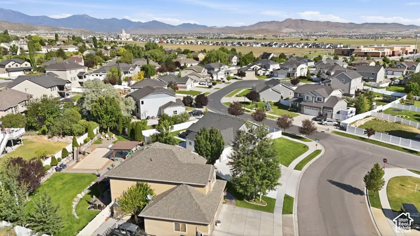 Curved street design, extensive residential housing, distant mountainous terrain, and open green spaces
