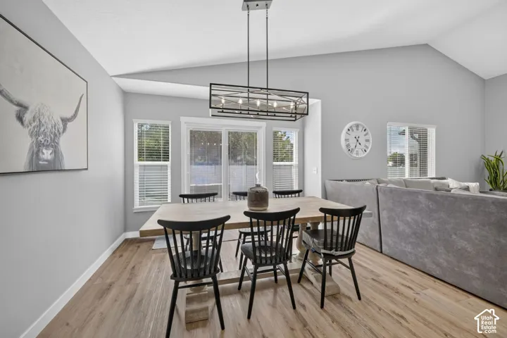 Vaulted ceilings, wood-finish flooring, and multiple windows with blinds
