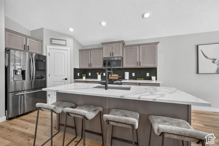 Kitchen featuring a center island with a white patterned countertop, wood-finish flooring, recessed lighting, and stainless steel appliances