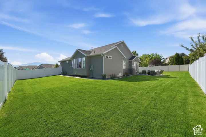 Expansive fenced backyard with a large lawn and mature trees