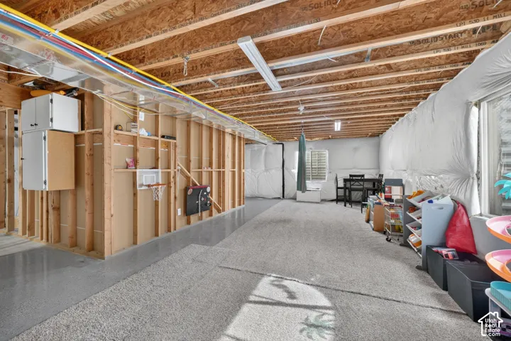Spacious unfinished basement with exposed beam ceiling, concrete flooring, and framed wall sections ready for customization