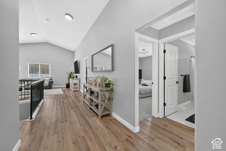 Vaulted ceilings, wood-finish flooring, white doors, black railing, and recessed lighting