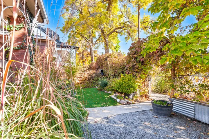 Brick exterior with climbing ivy accents, gravel hardscaping, artificial turf, and a mature treeline