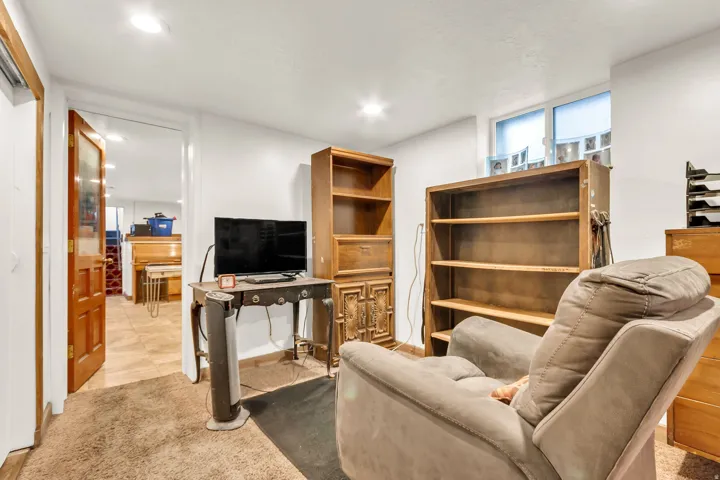 Recessed lighting illuminates this room, featuring a window and a doorway with a wood-panel door