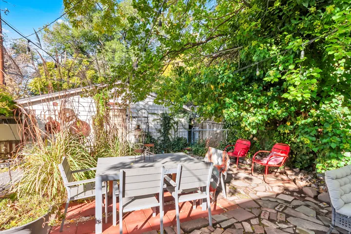 Patio area featuring a stone and brick floor, mature trees, and string lighting
