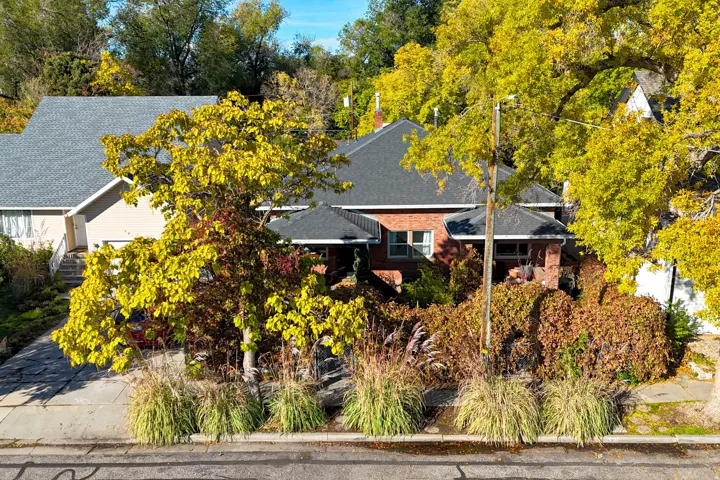Brick exterior with a dark-pitched roof, complemented by surrounding mature trees and layered landscaping