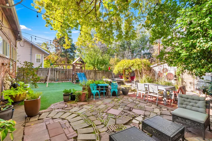 Expansive outdoor space featuring a paved patio, artificial turf, and mature trees
