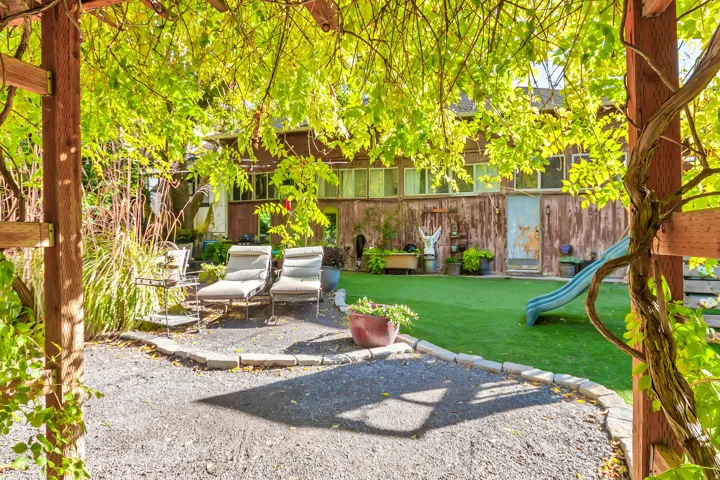 Pergola-covered gravel patio with adjacent artificial turf area