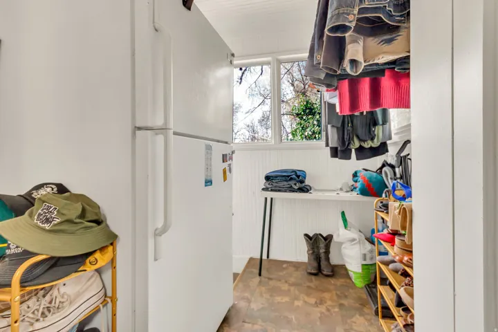 Compact utility space featuring a full-size refrigerator, beadboard paneling, and wood-finish flooring