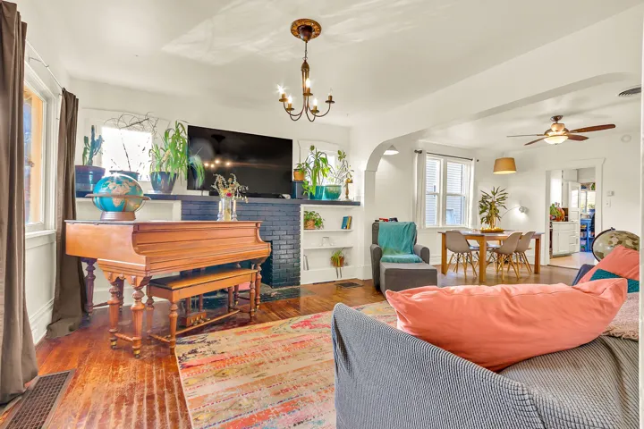 Hardwood flooring, arched doorway, built-in shelving, ceiling fan, and chandelier