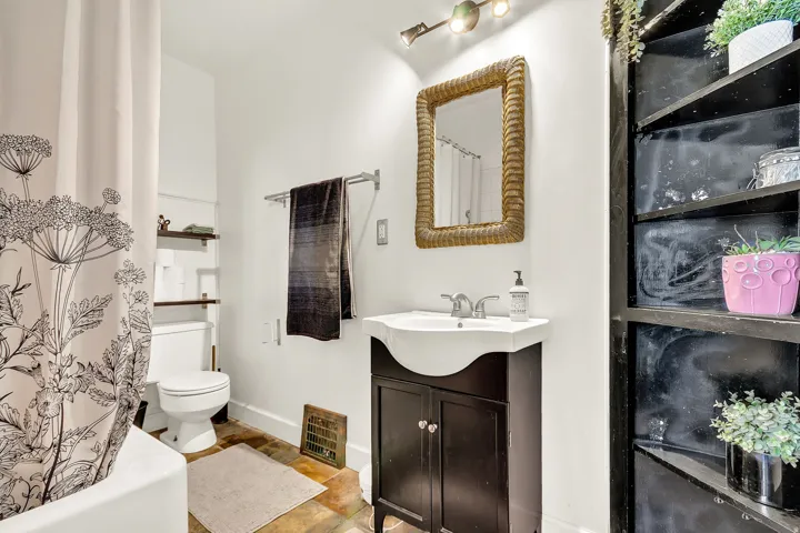 Bathroom featuring a pedestal sink with dark wood-finish vanity, wall-mounted mirror, track lighting, and built-in shelving