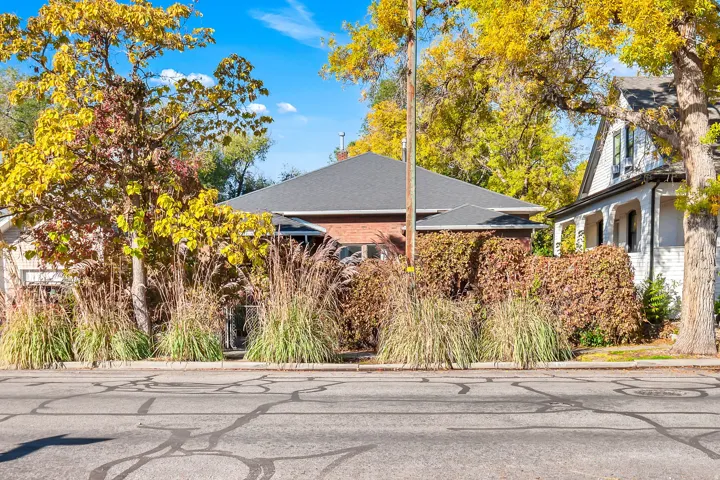 Brick exterior with a dark-pitched roof, complemented by mature deciduous trees