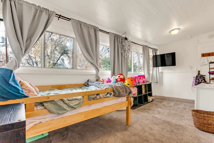 Wall-mounted television, chandelier light fixture, built-in shelving, white beadboard ceiling, and gray carpeting